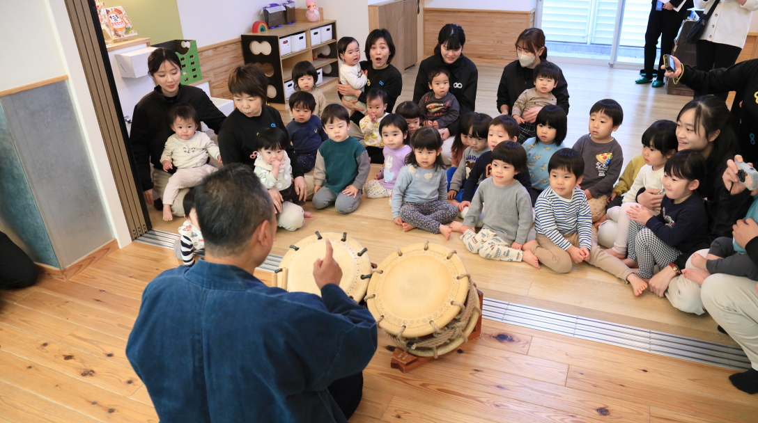 太鼓の音を聞くこどもたちの写真