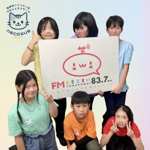 色違いのTシャツを着た子供たちがFMとまこまいのプラカードを持っている写真