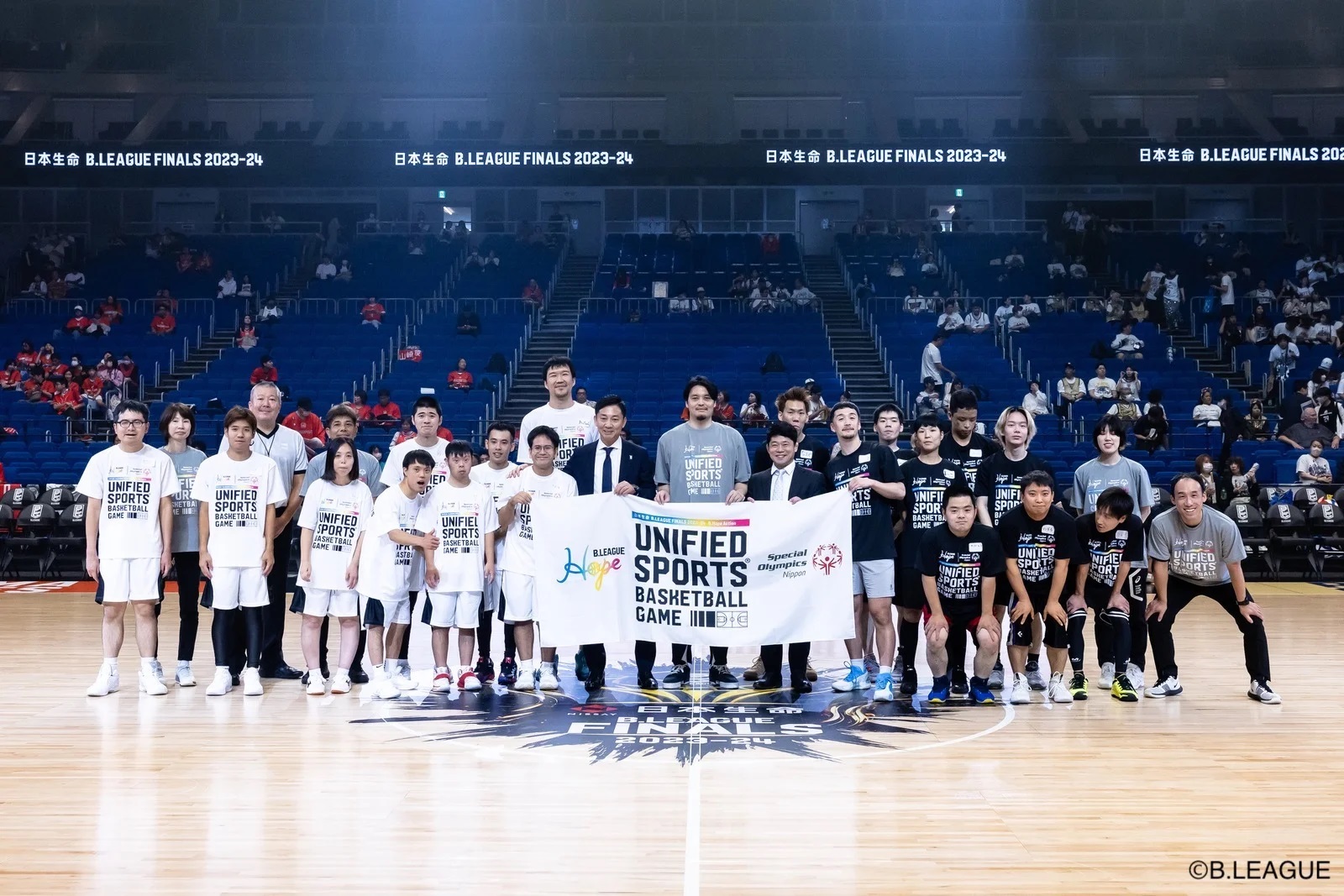 中心にUNIFIED SPORTS BASKETBALL GAMEと書かれたものを持って集合写真を撮っている様子