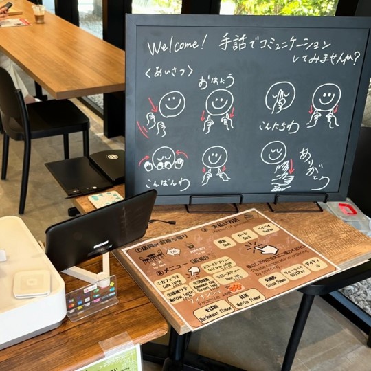 小さな黒板に手話でコミュニケーションしてみませんか？とあり、手話のイラストが描かれている