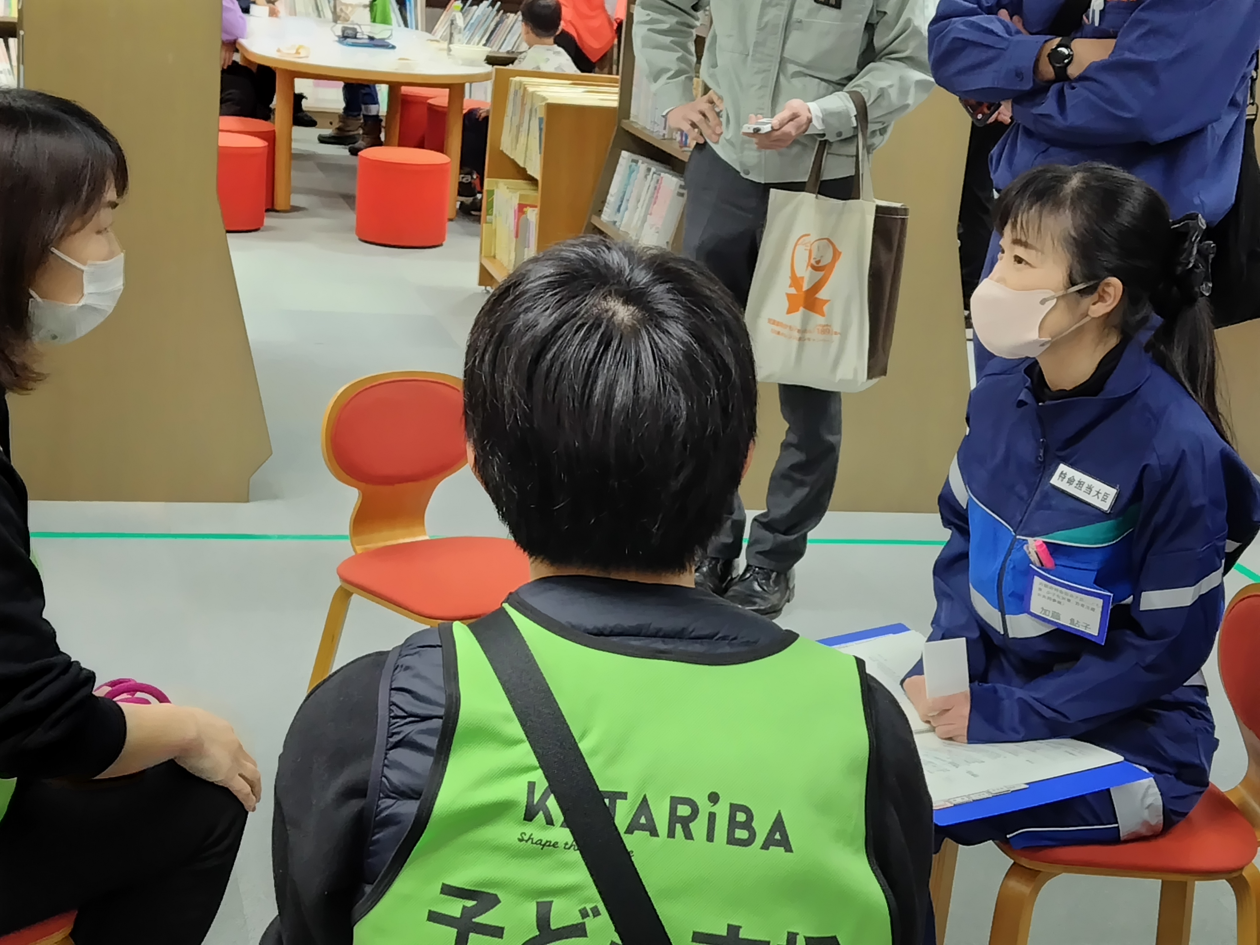 1次避難所において、こどもの居場所づくりに取り組むNPO法人や居場所を利用しているこどもたち、ご自身のクリニックや避難所において被災した女性の支援に取り組まれている医師の方と加藤大臣の意見交換の様子